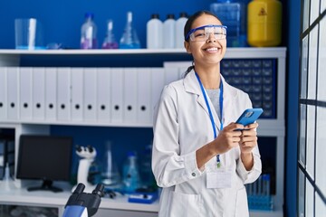 Young african american woman scientist using smartphone at laboratory