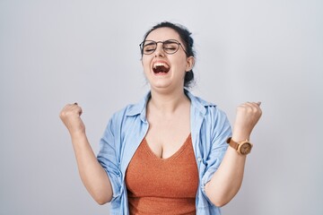 Young modern girl with blue hair standing over white background very happy and excited doing winner gesture with arms raised, smiling and screaming for success. celebration concept.