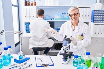 Middle age woman working at scientist laboratory celebrating achievement with happy smile and winner expression with raised hand