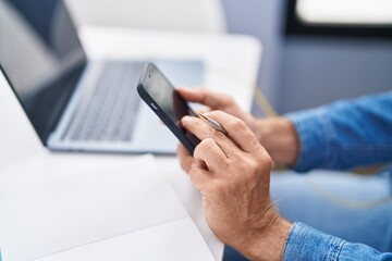 Young man sitting on table using smartphone studying at home