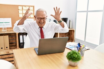 Senior man business worker using laptop with winner expression at office