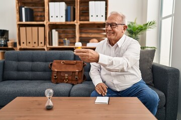 Senior man psychologist smiling confident prescribe pills at psychology center