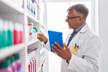 Middle age grey-haired man pharmacist using touchpad working at laboratory