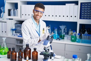 Fototapeta premium African american man scientist writing on document at laboratory