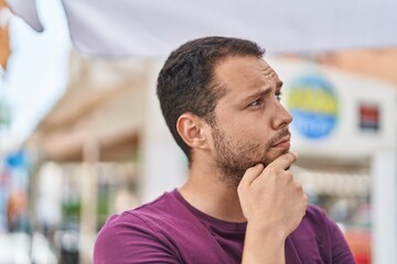 Young man standing with doubt expression at street