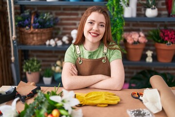 Young redhead woman florist smiling confident sitting with arms crossed gesture at flower shop