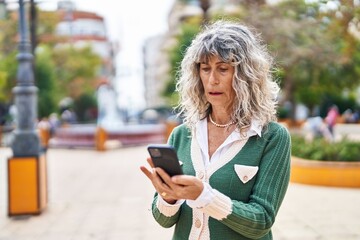 Middle age woman using smartphone at park