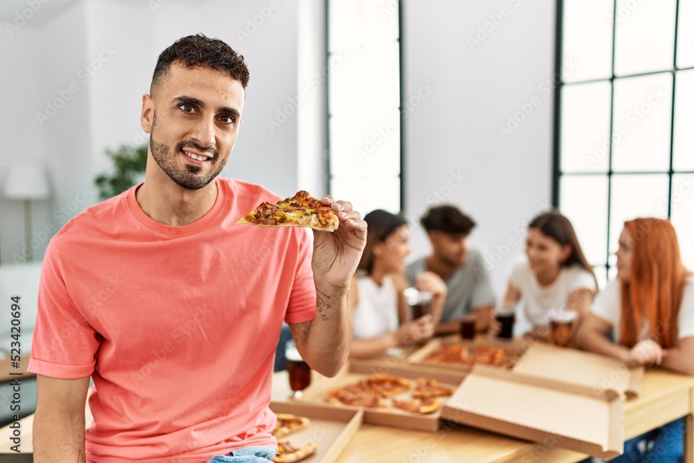 Sticker group of young people smiling happy eating italian pizza sitting on the table at home