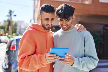 Two man couple hugging each other using touchpad at street