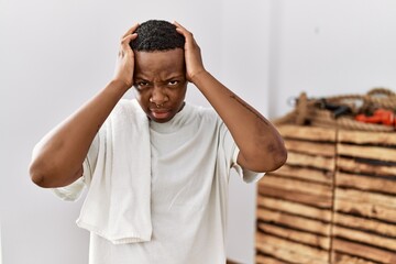 Young african man wearing sportswear and towel suffering from headache desperate and stressed because pain and migraine. hands on head.