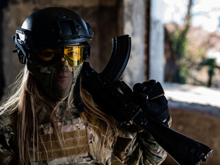 Portrait of a woman in a helmet and goggles with a machine gun in her hands. A female soldier in a...