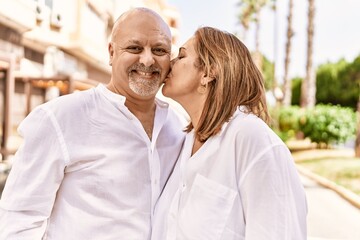 Fototapeta premium Middle age hispanic couple of husband and wife together on a sunny day outdoors. Kissing in love at the city