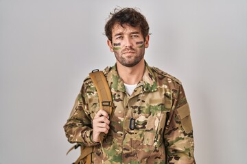 Hispanic young man wearing camouflage army uniform skeptic and nervous, frowning upset because of...