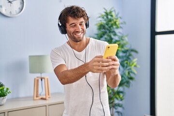 Young man listening to music standing at home