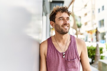 Young hispanic man smiling confident leaning on wall at street