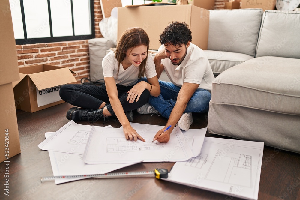 Sticker man and woman couple smiling confident looking house plans at new home