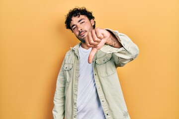 Young hispanic man wearing casual clothes looking unhappy and angry showing rejection and negative with thumbs down gesture. bad expression.