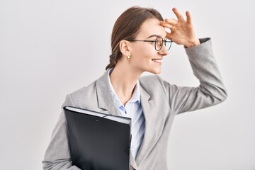 Young caucasian woman wearing business clothes and glasses very happy and smiling looking far away with hand over head. searching concept.