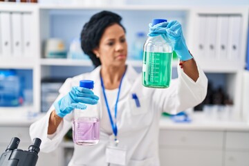 African american woman wearing scientist uniform measuring liquid at laboratory