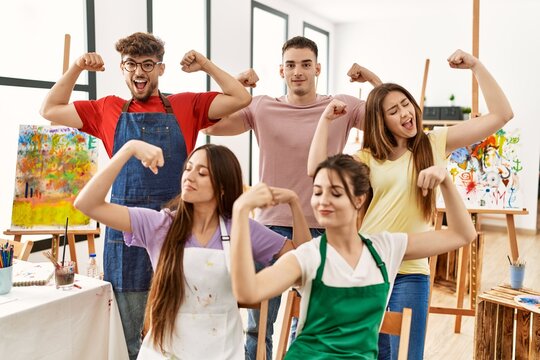 Group of five hispanic artists at art studio showing arms muscles smiling proud. fitness concept.