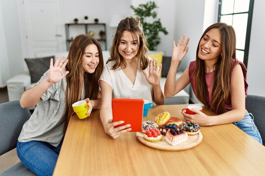 Three young hispanic woman smiling happy having breakfast and video call using touchpad at home.