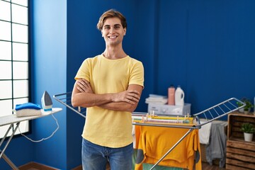 Young man doing laundry smiling with a happy and cool smile on face. showing teeth.