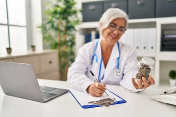 Middle age woman wearing doctor uniform prescribe marihuana at clinic
