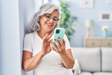 Middle age woman using smartphone standing at home