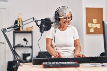 Middle age woman musician playing keyboard piano at music studio