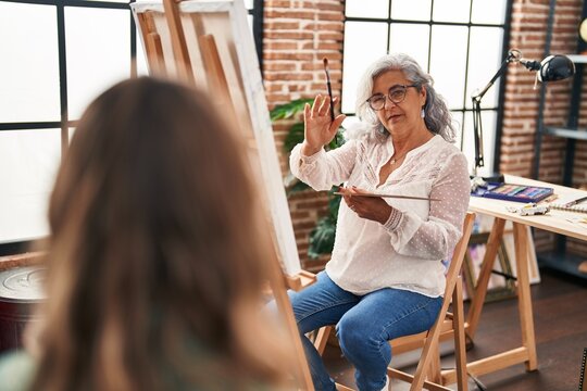 Middle age woman artist drawing portrait of person at art studio