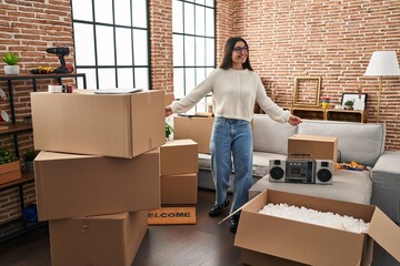 Young hispanic woman smiling confident standing with arms open at new home