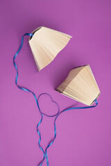 Old books and blue ribbons on bright purple background. Education, knowledge or nature concept....