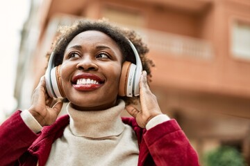 Beautiful african american woman with afro hair smiling happy and confident wearing headphones listening to music