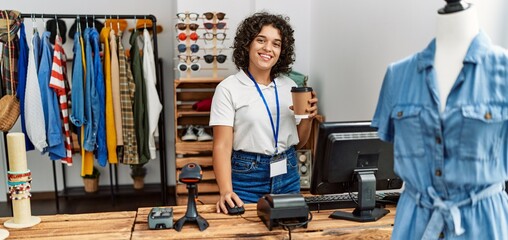 Young latin shopkeeper woman smiling happy working  and drinking coffee at clothing store.