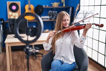 Young caucasian woman musician having online violin lesson at music studio