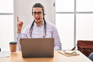 Hispanic man with long hair working using computer laptop smiling with an idea or question pointing finger up with happy face, number one