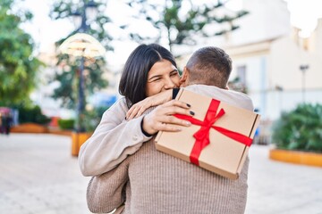 Man and woman couple smiling confident surprise with gift at park