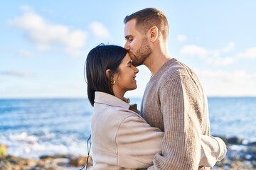 Man and woman couple smiling confident hugging each other kissing at seaside