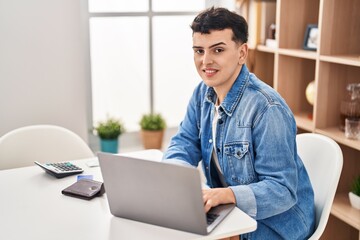 Fototapeta premium Young non binary man sitting on table doing the accounting at home