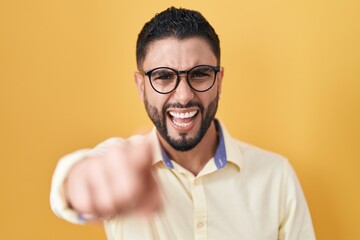 Hispanic young man wearing business clothes and glasses pointing displeased and frustrated to the camera, angry and furious with you