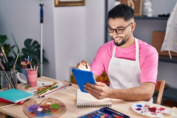 Fototapeta premium Young arab man artist drawing on notebook using touchpad at art studio