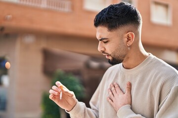 Young arab man smoking and coughing at street
