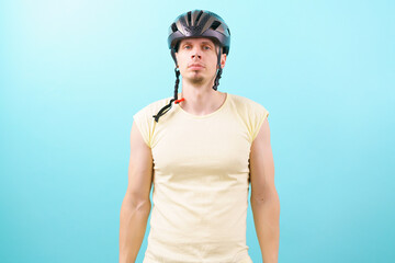 A young man wearing a bicycle stands on a blue background. Bicycle. Bicyclist. Bike. Biker. Biking. Blue. Care. Control. Crash. Cycling. Cycling Helmet. Cyclist. Defense. Equipment. Guy. Head
