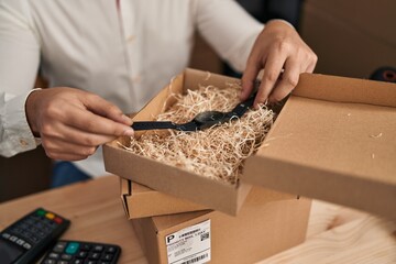 Young hispanic man e-commerce business worker packing watch at office