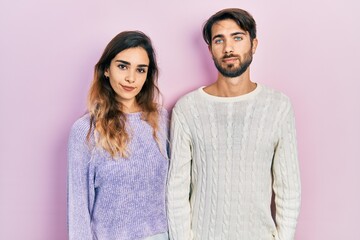 Young hispanic couple wearing casual clothes relaxed with serious expression on face. simple and...
