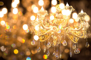 Close up on crystal of contemporary chandelier, is a branched ornamental light fixture designed to...