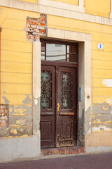 Fototapeta na wymiar Just off an Osijek Street in Croatia is this old apartment building in yellow with old brown double doors.