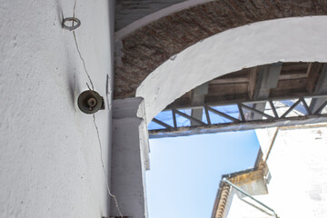 Fototapeta na wymiar Mechanically operated doorbell on a torsion spring actuated by a wire. Bell nailed to whitewashed wall