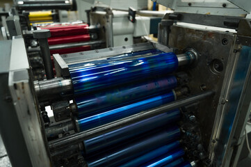Cyan ink in the paint system compartment of a modern flexographic printing press in a print shop....