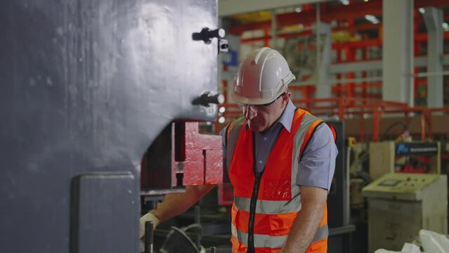 Professional industrial, Man workers working on machines, Heavy Industry, Men wearing safety uniforms and hard hats are 48-year-old.